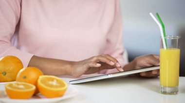 Tablet, portakal ve meyve suyu masada, sağlık makale arama kullanarak karma yarış lady