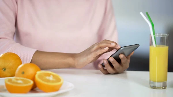 Monirotuinen Tyttö Käyttää Älypuhelinta Keittiössä Appelsiinit Pöydällä Terveydenhuollon Ruoka — kuvapankkivalokuva