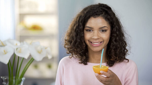 Happy mixed race young lady holding orange half, immune system protection, diet