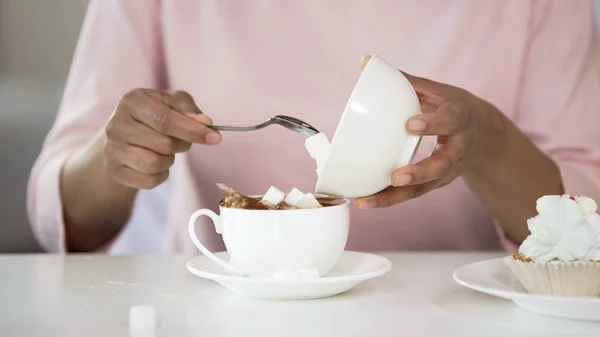 Young woman adding too much sugar in tea cup, unhealthy lifestyle, diabetes