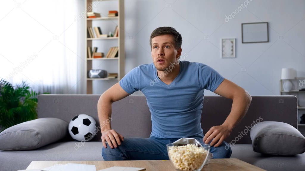 Excited football fan attentively watching players on field on tv, semi-final
