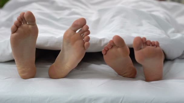 Esposo y esposa acostados en la cama y tocando piernas, relación y confianza, amor — Vídeos de Stock