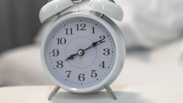 Reloj despertador blanco de pie en la mesa cerca de la cama, fecha límite, gestión del tiempo, primer plano — Vídeos de Stock