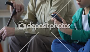 Smartphone oyun oynarken, dedesi ile oturan bıkkın duygu okullu çocuk