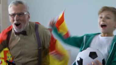 Futbol maçı, İspanya bayrağı sallayarak hayranları izlerken Büyükbaba ile heyecanlı küçük çocuk
