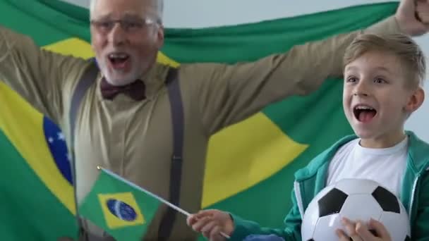 Стара людина з онука, підтримці Бразилії футбольної команди ТБ матчу, сім'ї хобі — стокове відео