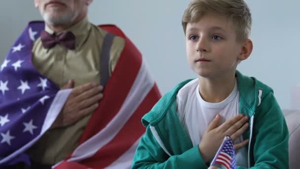 Patrioti maschi ascoltano inno americano che tiene per mano il cuore, partita di calcio tv — Video Stock