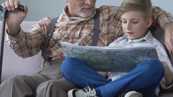 School jongen leren wereldkaart met grootvader hulp, gepensioneerde m/v kennisdeling — Stockvideo