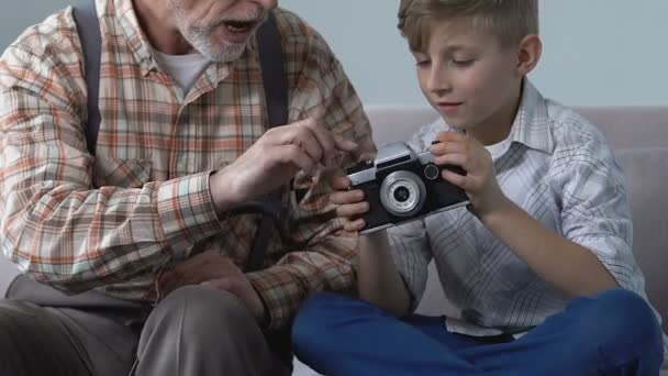 Дідусь показує хлопчика старовинну фотокамеру, творче сімейне хобі, дозвілля — стокове відео