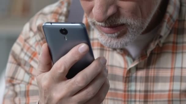 Hombre mayor leyendo el mensaje en el teléfono inteligente, mala vista, tecnología moderna — Vídeo de stock