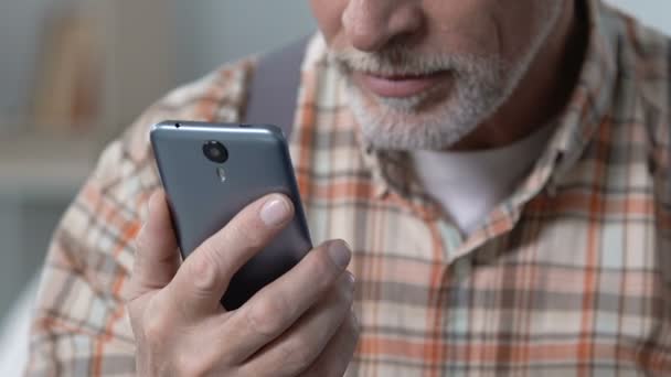 Abuelo en gafas aprendiendo a usar el teléfono inteligente, viendo video en línea — Vídeos de Stock
