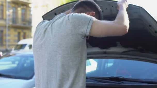 Человек, вызывающий эвакуацию, смотрит под капот своей машины, проблемы со срывом — стоковое видео