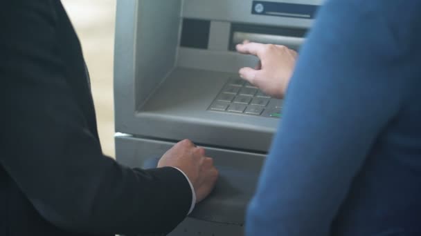 Сотрудница банка показывает новому клиенту, как работать с банкоматом, хороший сервис — стоковое видео