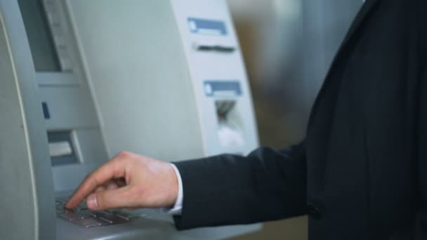 Mężczyzna podczas pisania kodu pin na klawiaturze bankomatu, aby wycofać dolarów z konta bankowego — Wideo stockowe