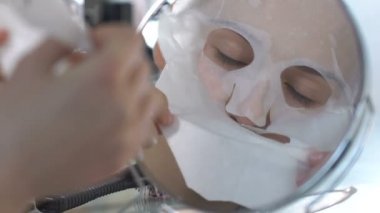 Ayna, mükemmel cilt nemlendirici doku maskesini önünde alarak güzel kız