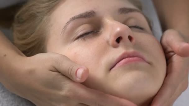 Ženské masér masíruje klientovi bradu, zlepšuje tón pleti a tvarování svalů — Stock video
