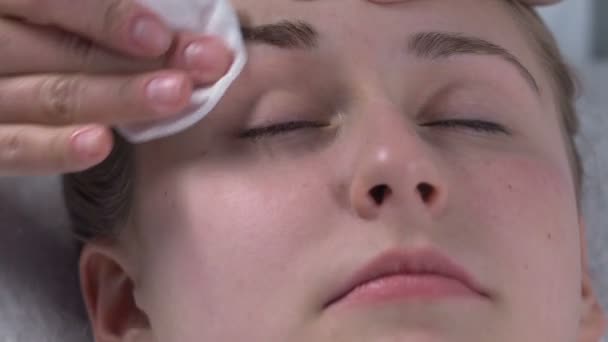 Kosmetikerin wischt Augenbrauenfarbe ab, entfernt Make-up, Gesichtsdesinfektionshygiene — Stockvideo