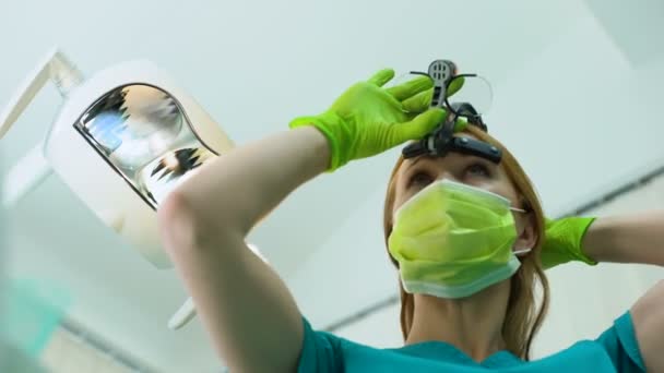 Jeune femme dentiste en loupes examinant la cavité buccale, patiente POV — Video