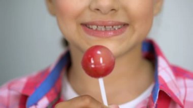 Kız lolipop, dişler, diş bakımı kavramı üzerinde kötü etkisi şeker ısırmaya çalışıyor