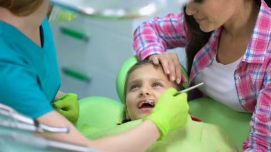 Çocuk diş muayenesi, doktor ve küçük kız yatıştırıcı üst korkuyor