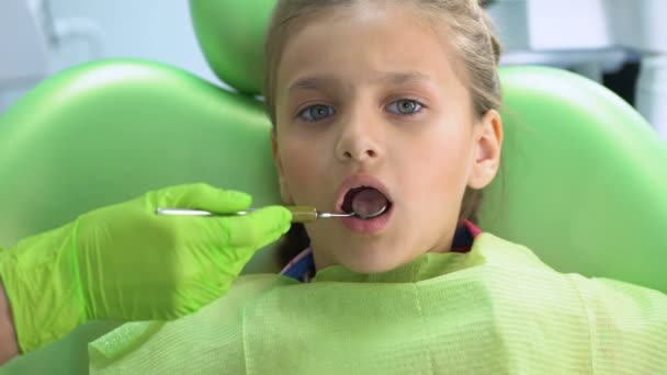 Odontólogo pediátrico revisando dientes con espejo bucal, examen dental de rutina — Vídeo de stock