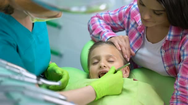 Niña en examen dental regular, madre sosteniendo hija, calmante — Vídeos de Stock