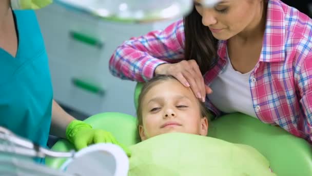 Очаровательный ребенок улыбается после стоматологических процедур, смотрит на здоровые зубы в зеркале — стоковое видео