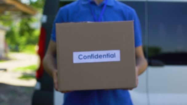 Confidential parcel courier in uniform holding cardboard box, document shipping — Stock Video