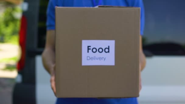 Доставка еды курьер мужского пола держит картонную коробку, онлайн заказ, торговые услуги — стоковое видео