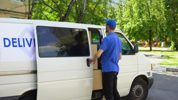 Работник почтового отделения забирает посылку из фургона и показывает большие пальцы вверх — стоковое видео