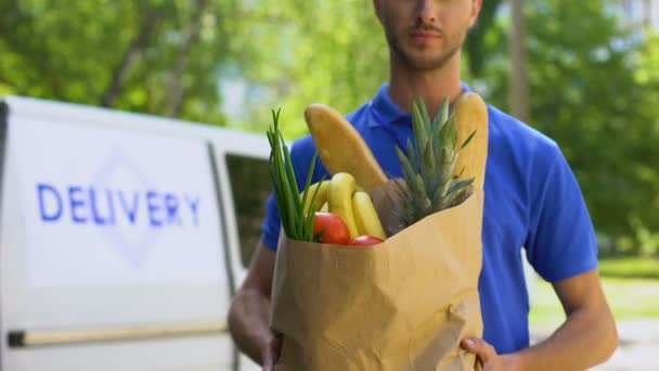 Jovem entregador mostrando saco de supermercado, serviço de loja, envio de pedidos on-line — Vídeo de Stock