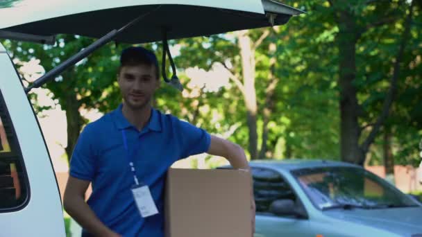 Young delivery man holding parcel, showing thumbs up, fast shipping service — Stock Video