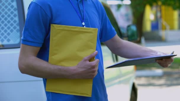 Mujer firma formulario de entrega de prueba y recibir paquete amarillo de mensajero — Vídeo de stock