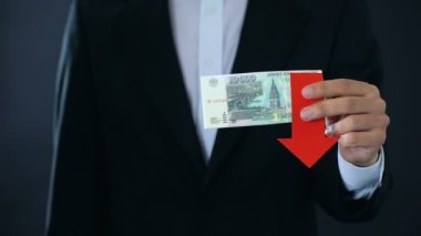 Başparmak yukarı ve aşağı gösterilen, düşen Rus Rublesi banknotlar tutan işadamı