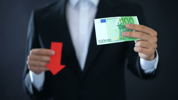 Uomo d'affari che mostra banconote in euro e cartelli con frecce rosse, caduta di valuta, crisi — Video Stock