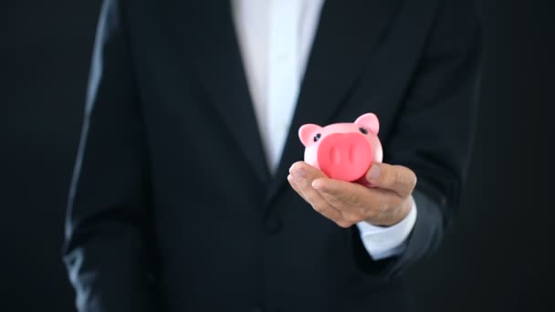 Homem colocando nota de dólar em banco porquinho, conta poupança, renda de depósito bancário — Vídeo de Stock