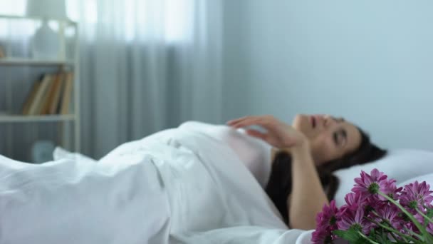 Mulher acordando na cama para ver buquê de flores bonitas, agradável surpresa — Vídeo de Stock
