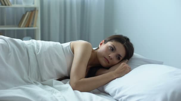 Грустная красивая женщина нежно гладит подушку рядом с ней, одиночество после развода — стоковое видео