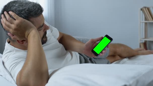 Hombre desplazándose páginas web de pantalla verde en el teléfono inteligente, en busca de nuevas aplicaciones — Vídeo de stock