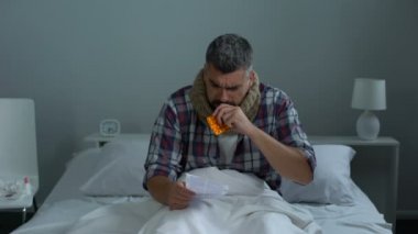Antiviral ilaçlar öksürük için talimat okuma adam yatakta oturup soğuk yakaladı