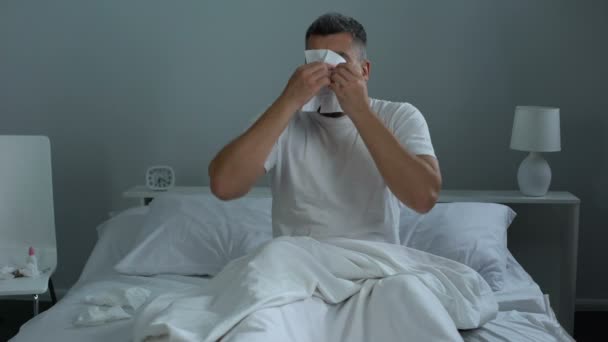 Мужчина с сезонной аллергией, чихает в постели, нуждается в антигистаминных препаратах, здравоохранении — стоковое видео
