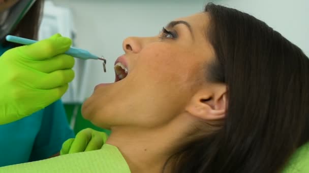 Dentista examinando los dientes de la mujer a través del espejo de la boca, señora satisfecha con los resultados — Vídeos de Stock