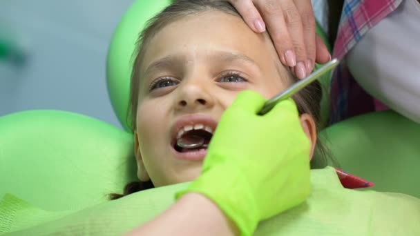 Мать утешает испуганную девочку во время стоматологического осмотра, дети боятся — стоковое видео