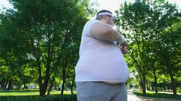 Obese person doing exercises in city park, jogging, personal training program — Stock Video