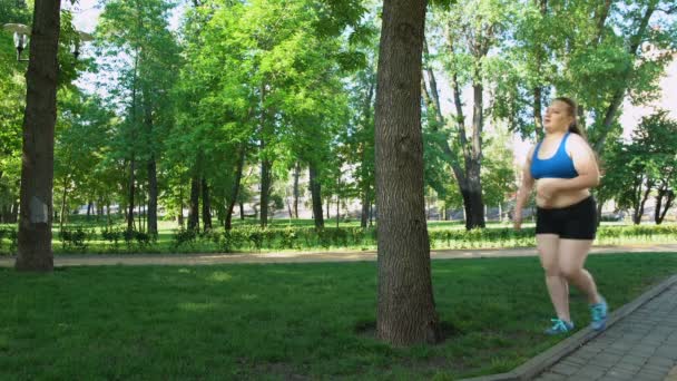 Obese girl tired after jogging, leaning on tree, tiresome workouts outdoors — Stock Video