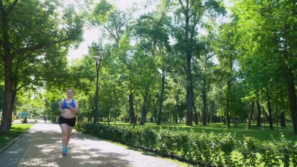 Vrij zwaarlijvige meisje joggen en glimlachend, zelfbewuste gemotiveerde persoon opleiding — Stockvideo