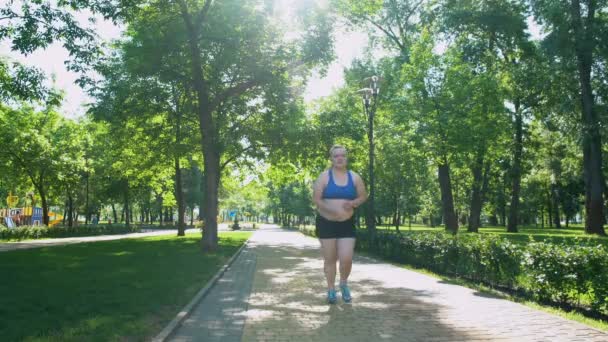 Menina obesa jogging, sufocante, sente dor de barriga após exercícios cansativos — Vídeo de Stock
