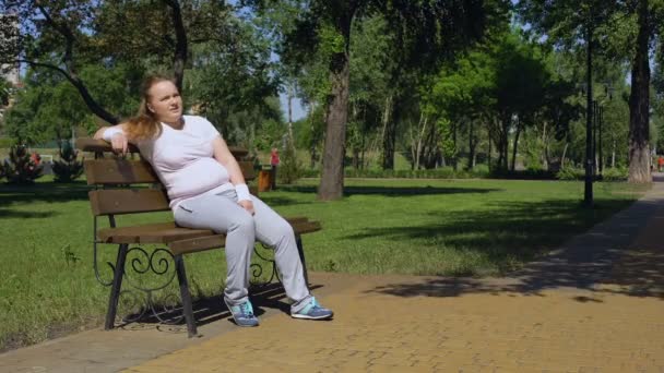 Gorda chica agotado después de trotar toma minutos de descanso en banco, la lucha contra la obesidad — Vídeo de stock