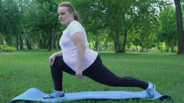 Τεντώνει παχύσαρκη κοπέλα στο πάρκο, καθημερινή ρουτίνα για την απώλεια βάρους, την επιθυμία να είναι λεπτή — Αρχείο Βίντεο