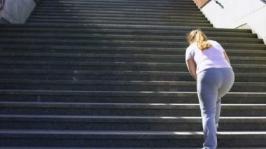 Obez kız, hedefe ulaşmak için yorgunluk üzerinde zafer için merdivenleri tırmanmaya zor